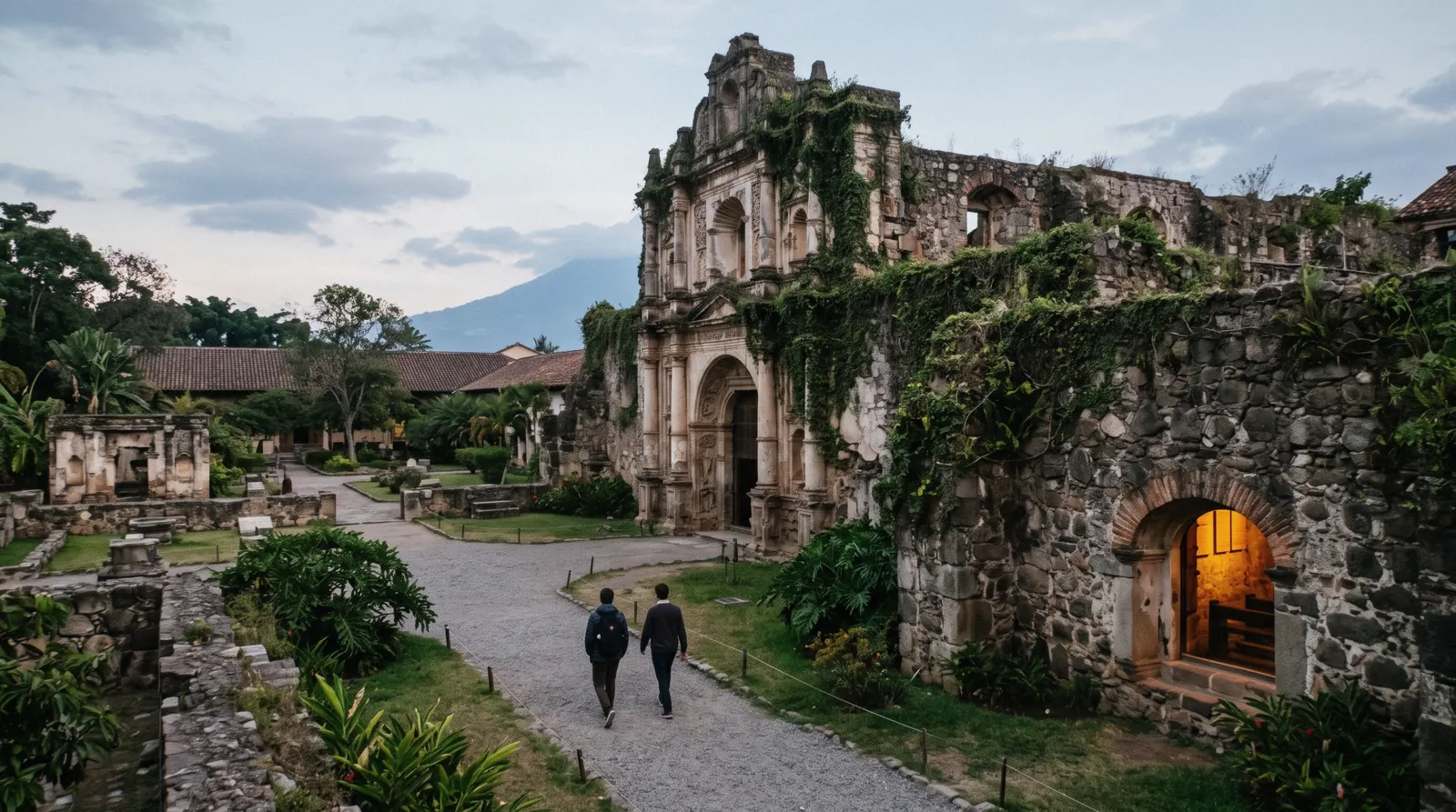 The stone church and grounds of the Santo Domingo monastery complex in Antigua Guatemala, ivy on the ruin walls, museum lamps warm in a crypt window