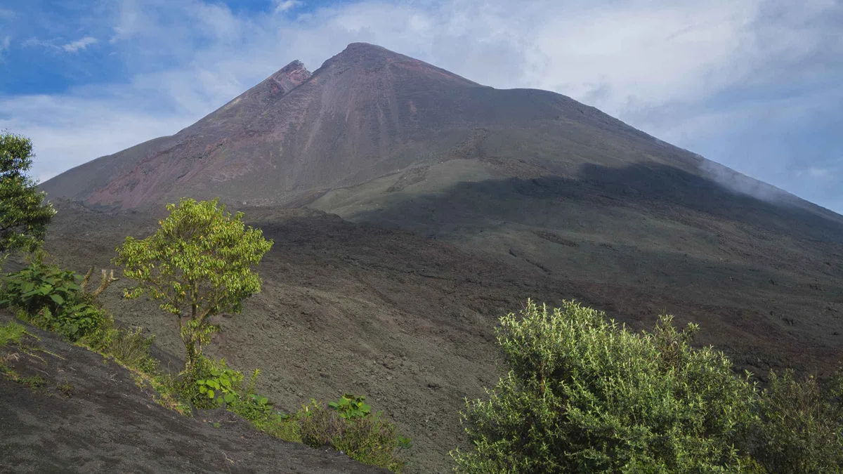 Tour shuttle group at the Pacaya volcano trailhead with the cone rising behind, Pacaya volcano day tour from Antigua Guatemala
