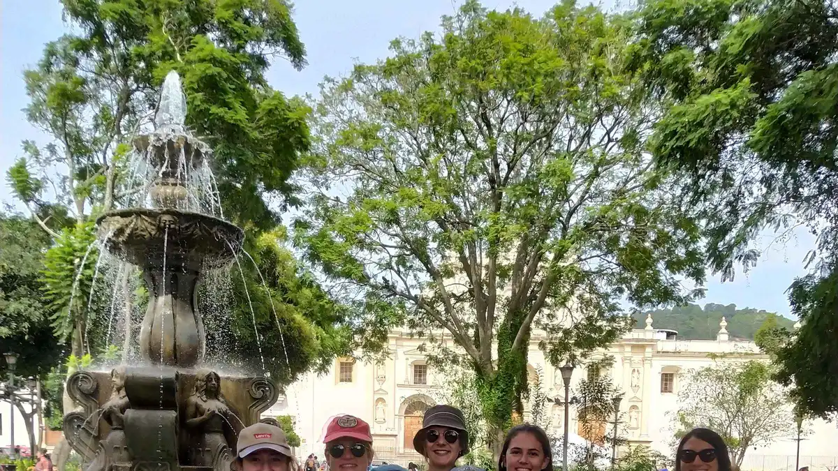 Guide leading a small walking group across Parque Central in Antigua Guatemala